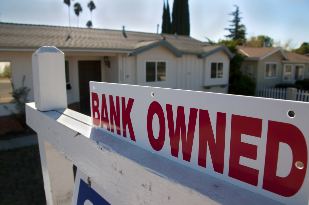 “Bank owned” foreclosure sign in front of a house.